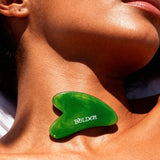 Green gua sha tool on a person's neck with 'BOLDEN' branding.