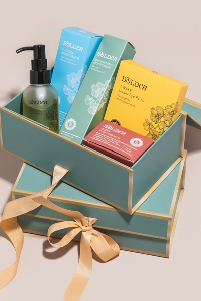 Collection of Bolden skincare products in a decorative box with a ribbon on a beige background