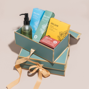 Collection of Bolden skincare products in a decorative box with a ribbon on a beige background