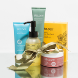 Collection of Bolden skincare products with a gold ribbon on a light gray background